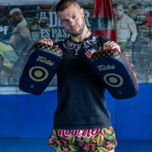 Coach wearing a Muay Thai belly pad and holding shields