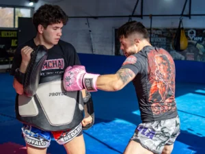 Coach holding focus mitts for a boxer during a pad round